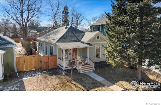 view of front of house with fence, covered porch, roof with shingles, and a gate