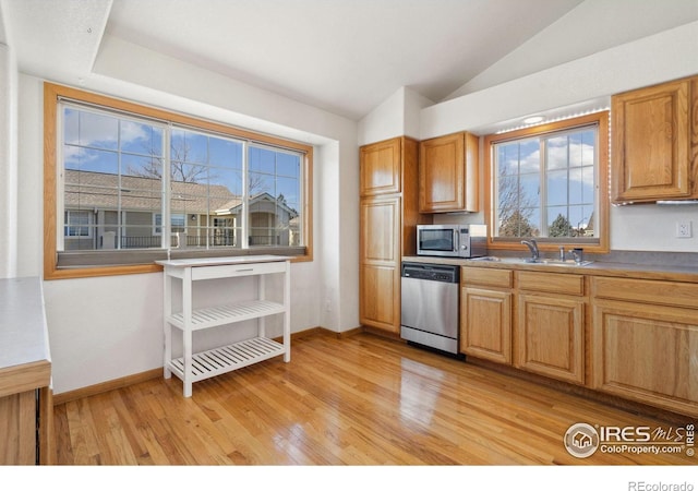 kitchen with stainless steel appliances, lofted ceiling, sink, and light hardwood / wood-style floors