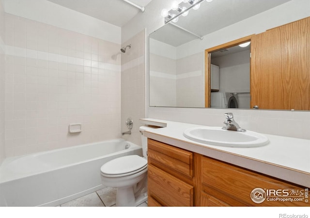 full bathroom featuring tiled shower / bath combo, vanity, washer / clothes dryer, tile patterned floors, and toilet