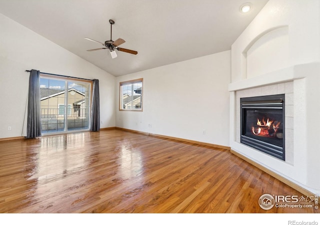 unfurnished living room with ceiling fan, lofted ceiling, a fireplace, and wood-type flooring