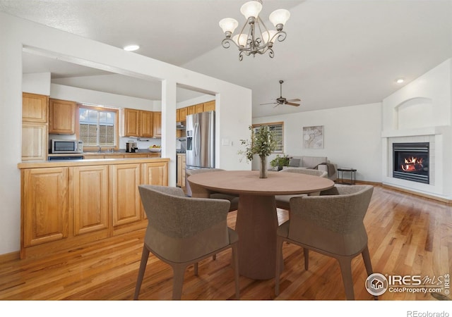 dining room featuring ceiling fan with notable chandelier and light hardwood / wood-style flooring