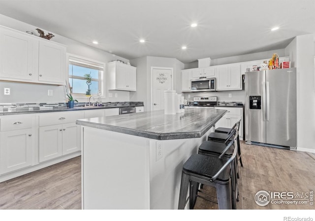 kitchen featuring light hardwood / wood-style flooring, a center island, white cabinets, and appliances with stainless steel finishes