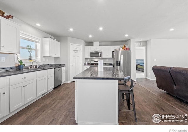 kitchen with sink, stainless steel appliances, a kitchen breakfast bar, white cabinets, and a kitchen island