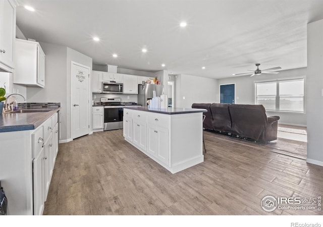 kitchen with sink, light hardwood / wood-style flooring, white cabinetry, stainless steel appliances, and a center island