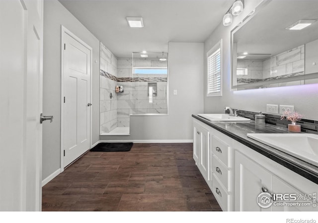 bathroom with hardwood / wood-style flooring, vanity, and tiled shower