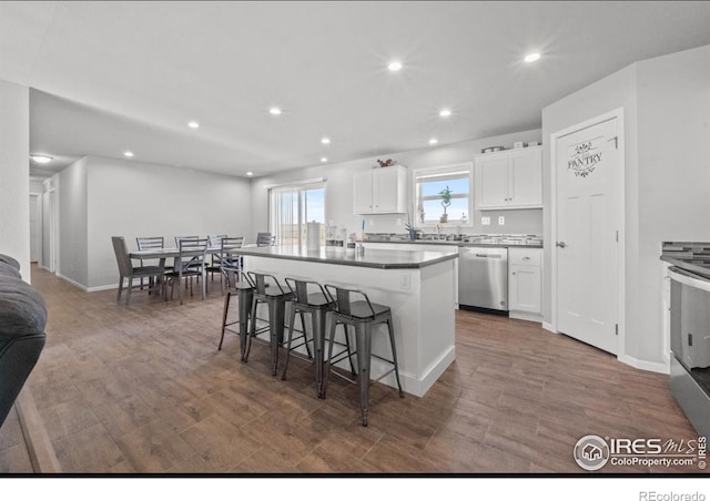 kitchen with a breakfast bar area, dark hardwood / wood-style flooring, a kitchen island, stainless steel appliances, and white cabinets