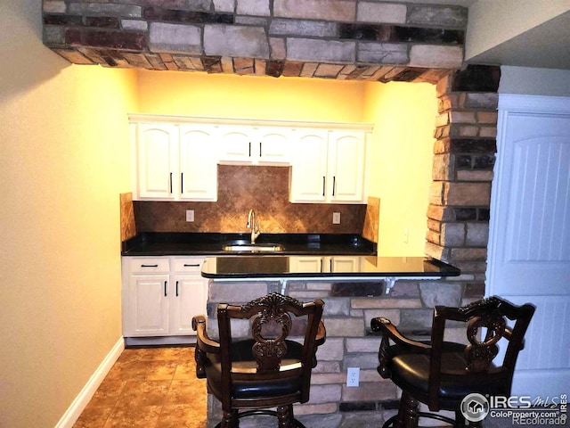 2023 81st Ave, Greeley, CO 80634 - kitchen featuring dark countertops, backsplash, white cabinets, and a kitchen bar