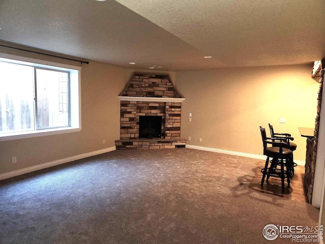 2023 81st Ave, Greeley, CO 80634 - unfurnished living room with carpet flooring, a stone fireplace, a textured ceiling, and recessed lighting