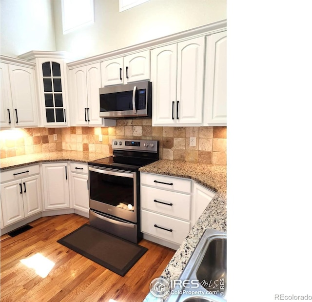 2023 81st Ave, Greeley, CO 80634 - kitchen featuring appliances with stainless steel finishes, light wood-style floors, white cabinets, and a high ceiling