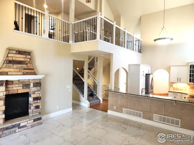2023 81st Ave, Greeley, CO 80634 - unfurnished living room with a high ceiling, stairway, light marble finish flooring, and a stone fireplace