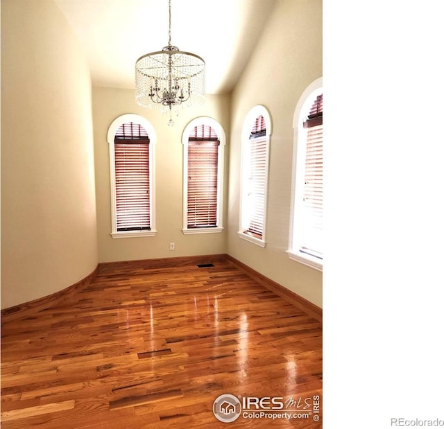 2023 81st Ave, Greeley, CO 80634 - unfurnished room with a chandelier, wood finished floors, and vaulted ceiling