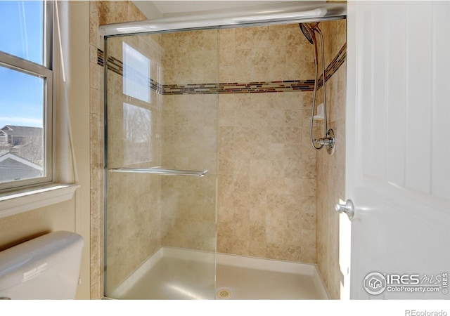 bathroom with a shower with shower door and toilet