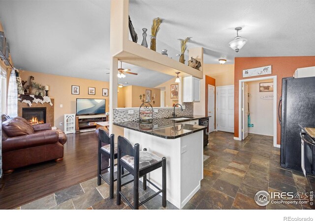 kitchen featuring lofted ceiling, sink, a breakfast bar area, white cabinets, and kitchen peninsula