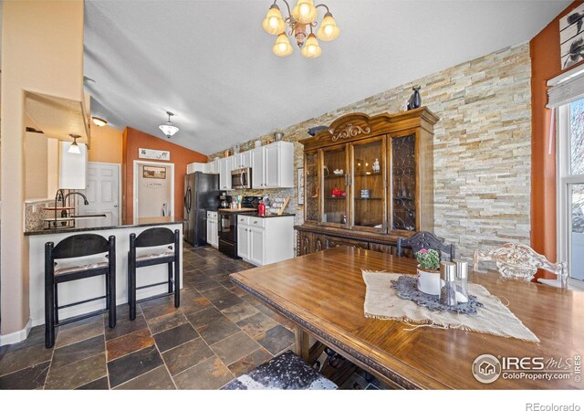 dining room with vaulted ceiling, sink, and a chandelier