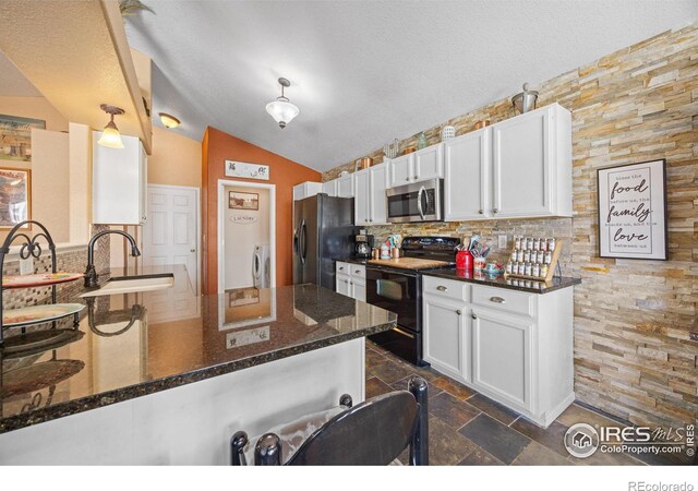 kitchen with sink, black appliances, dark stone countertops, kitchen peninsula, and white cabinets