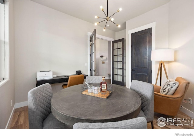 dining room featuring wood-type flooring and an inviting chandelier