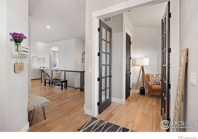 corridor featuring french doors and light hardwood / wood-style flooring