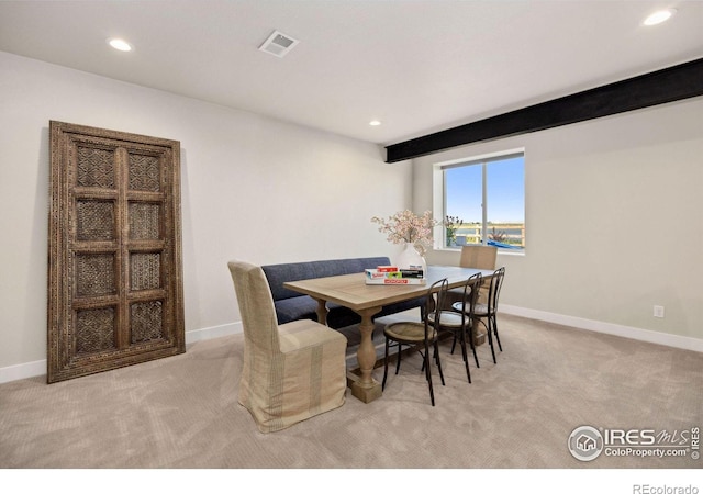 carpeted dining space featuring beamed ceiling