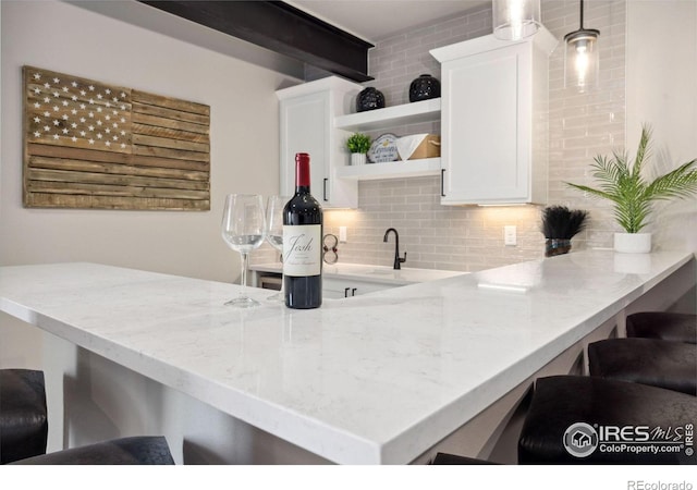 kitchen featuring white cabinetry, a breakfast bar, kitchen peninsula, and tasteful backsplash