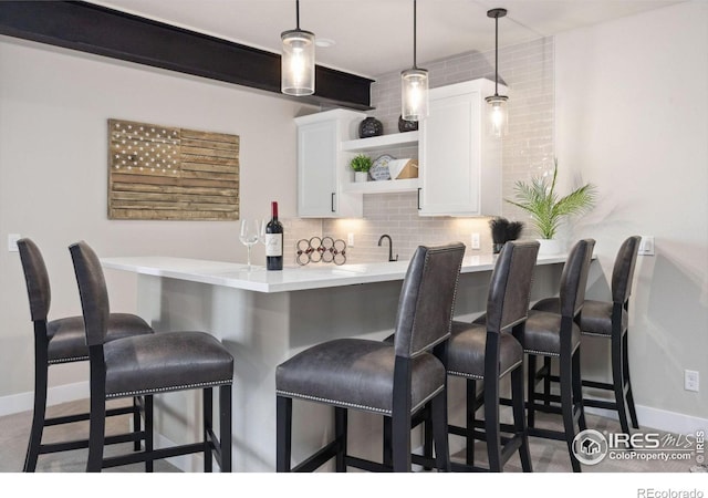 bar featuring white cabinetry, sink, pendant lighting, and tasteful backsplash