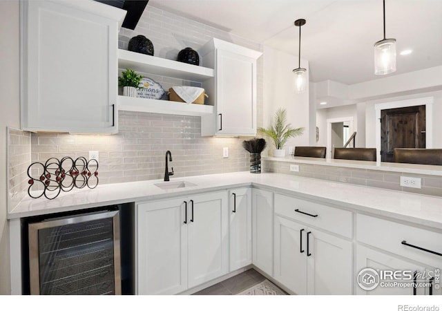 kitchen featuring white cabinets, light stone countertops, sink, and beverage cooler