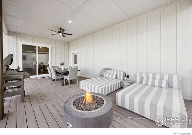 wooden deck with ceiling fan and a fire pit