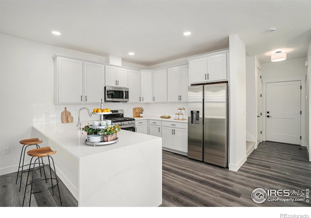 kitchen featuring appliances with stainless steel finishes, white cabinets, backsplash, and kitchen peninsula