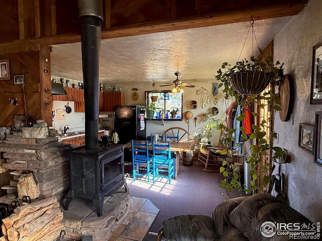 view of patio featuring a wood stove, sink, a textured ceiling, and ceiling fan