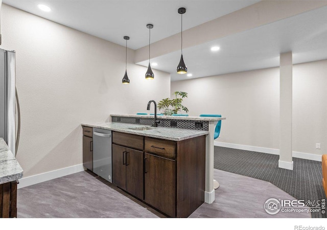 kitchen featuring appliances with stainless steel finishes, sink, light stone counters, kitchen peninsula, and dark brown cabinets