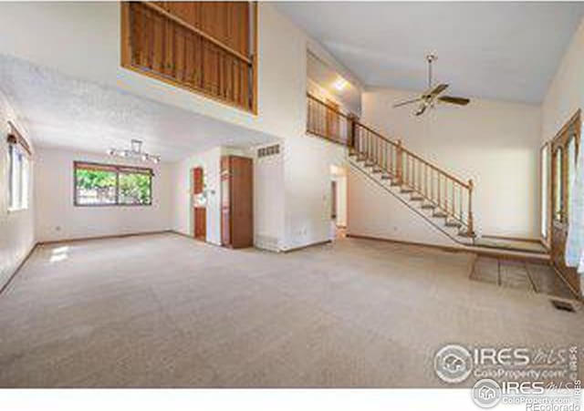 unfurnished living room featuring ceiling fan, a high ceiling, and carpet