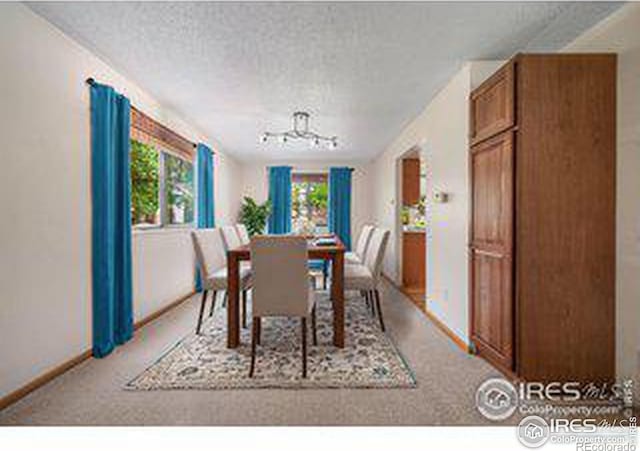 dining area featuring light colored carpet and a textured ceiling