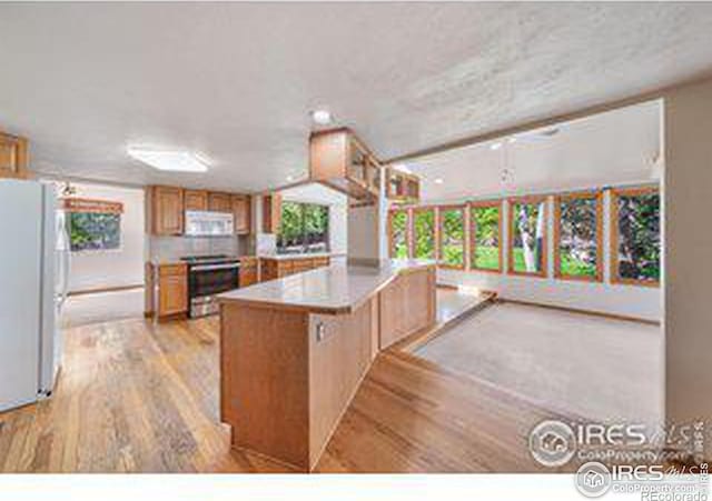 kitchen featuring white appliances, a kitchen island, and light hardwood / wood-style flooring