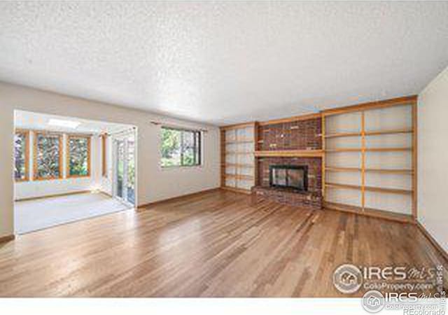 unfurnished living room with wood-type flooring, a textured ceiling, and a fireplace