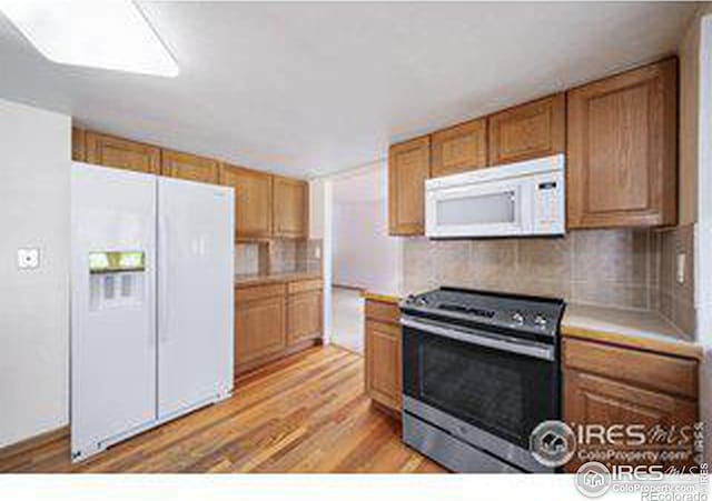 kitchen with white appliances, light hardwood / wood-style floors, and decorative backsplash