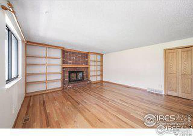 unfurnished living room with a brick fireplace and wood-type flooring