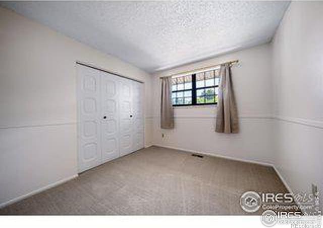 unfurnished bedroom featuring a closet, carpet floors, and a textured ceiling