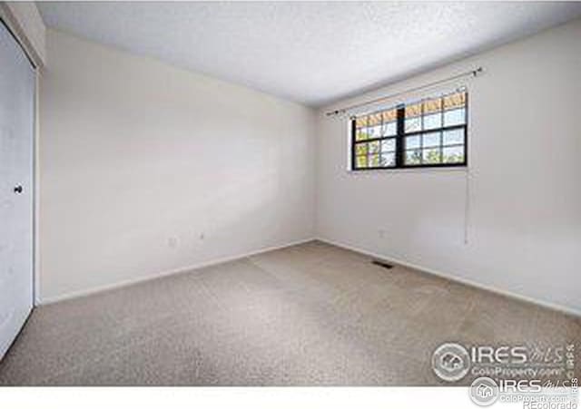 carpeted empty room with a textured ceiling