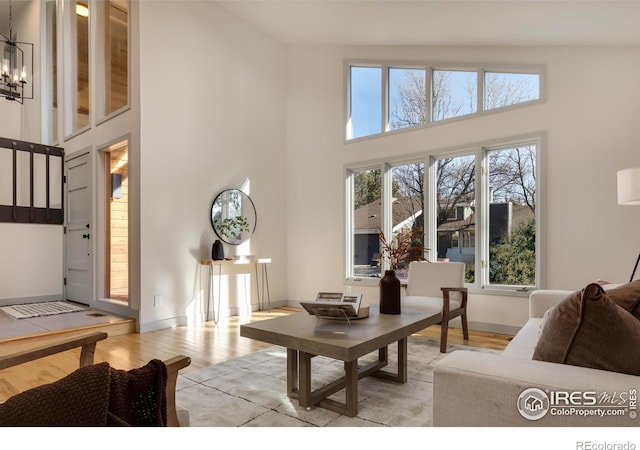 living room featuring a notable chandelier, a towering ceiling, and light hardwood / wood-style floors