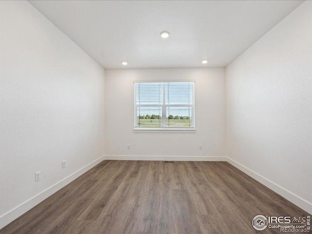 empty room with wood finished floors, baseboards, and recessed lighting