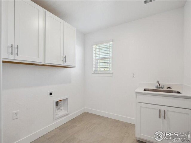 clothes washing area with hookup for an electric dryer, cabinet space, baseboards, and light floors