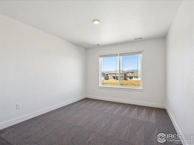 unfurnished room featuring dark carpet and baseboards