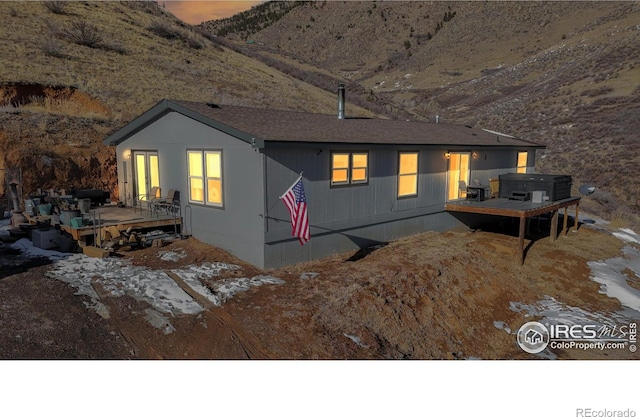 view of front facade featuring a hot tub and a deck with mountain view