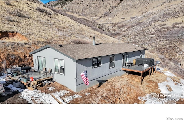 rear view of property with a wooden deck and a hot tub