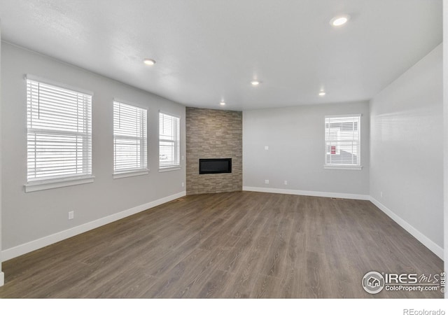 unfurnished living room featuring a large fireplace and dark hardwood / wood-style floors