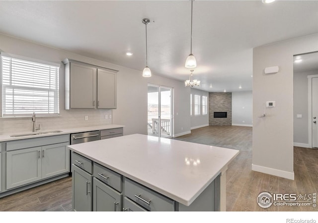 kitchen with gray cabinets, pendant lighting, tasteful backsplash, sink, and a center island