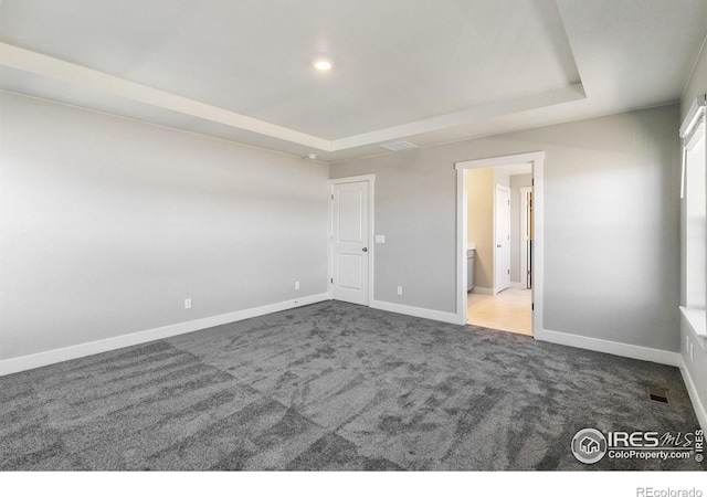 unfurnished bedroom featuring connected bathroom, carpet flooring, and a raised ceiling