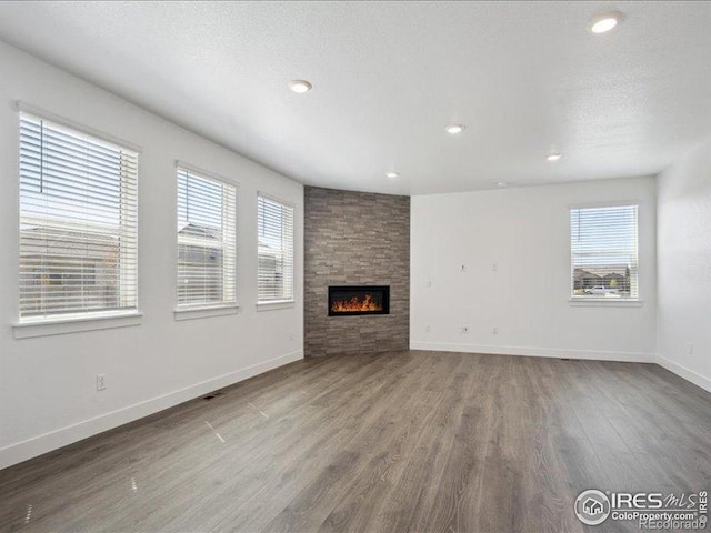unfurnished living room featuring wood finished floors, baseboards, a fireplace, and recessed lighting