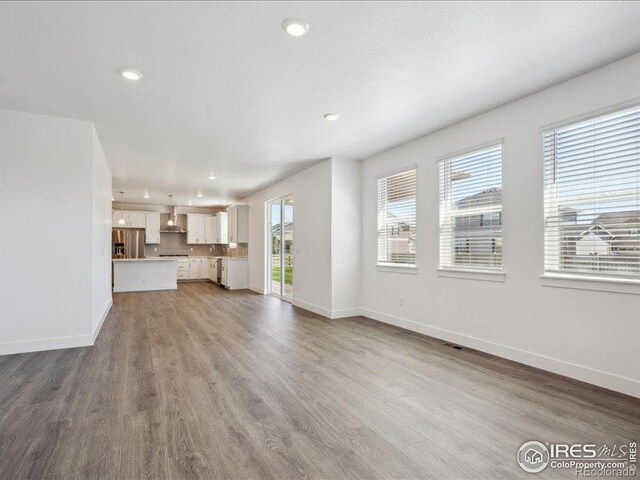 unfurnished living room featuring baseboards, recessed lighting, and wood finished floors
