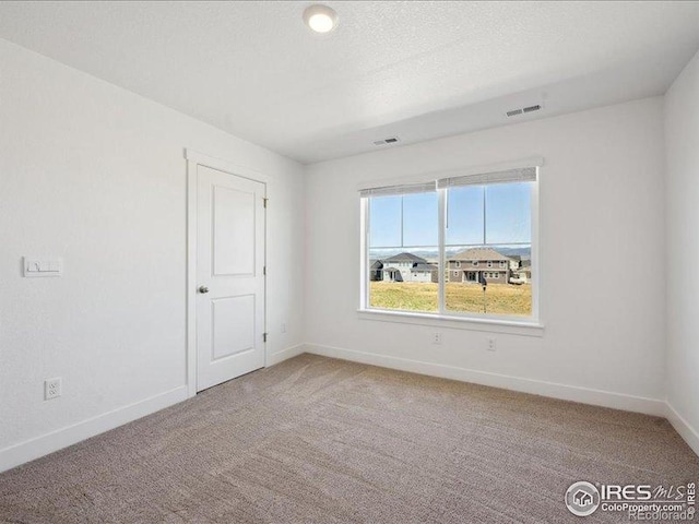 spare room featuring baseboards and light colored carpet