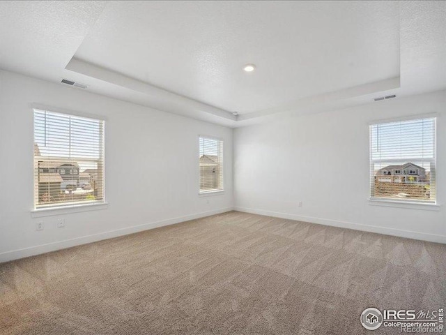 unfurnished room with a tray ceiling, baseboards, light colored carpet, and recessed lighting